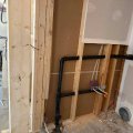 Exposed residential plumbing pipes installed along a basement wall
