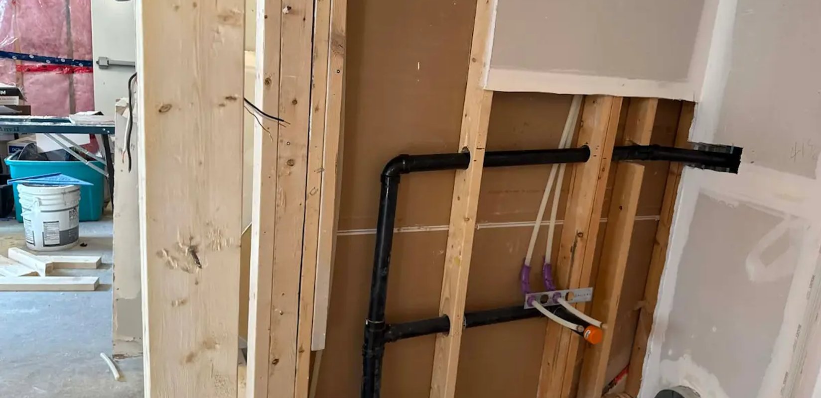 Exposed residential plumbing pipes installed along a basement wall