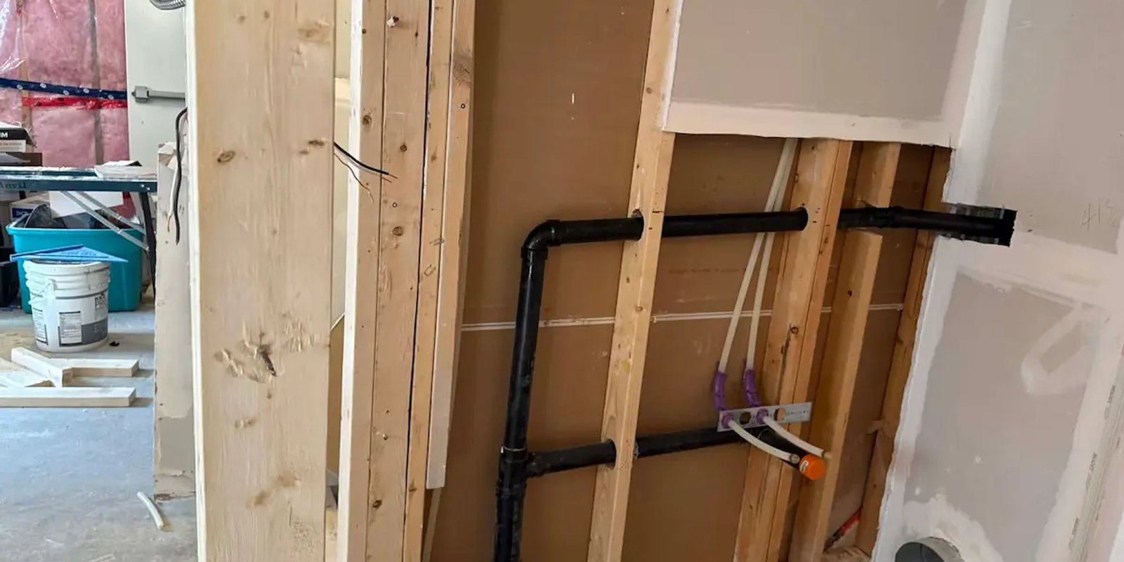 Exposed residential plumbing pipes installed along a basement wall