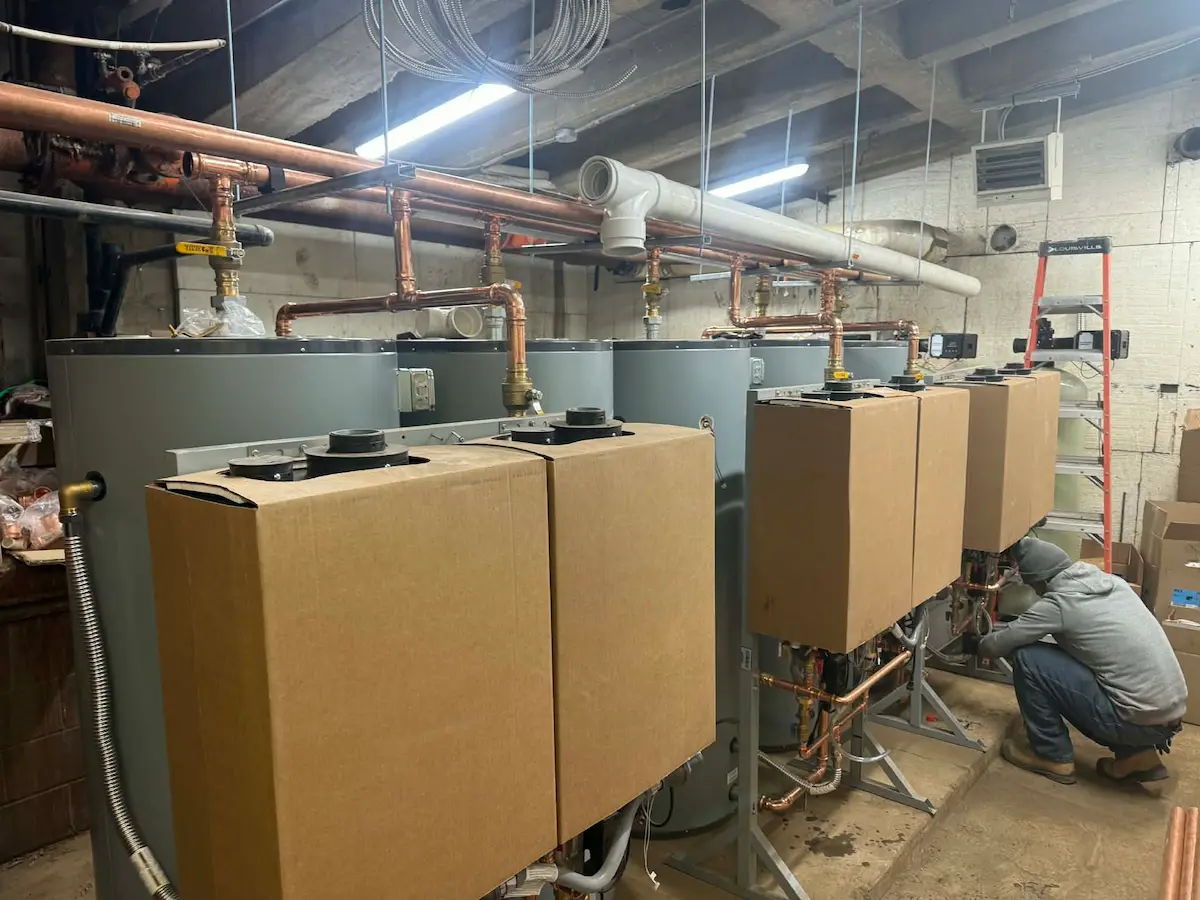 Technician working on Rinnai tankless water heater units in a mechanical room
