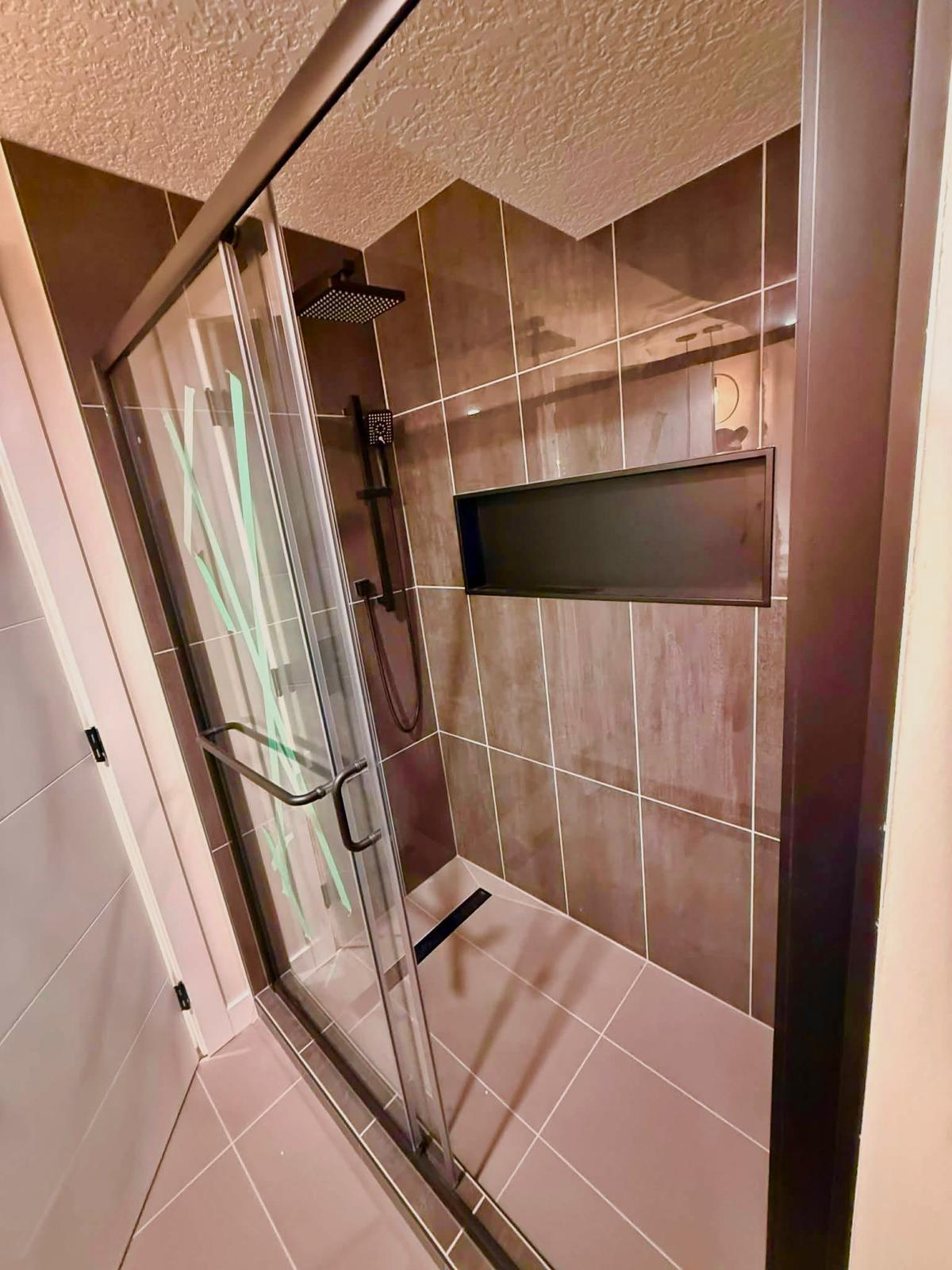 Finished bathroom shower renovation with tile walls and glass door