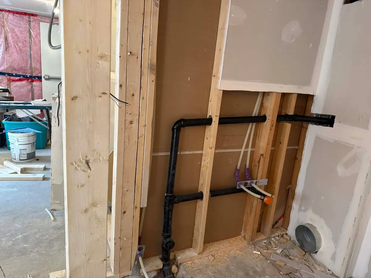 In-wall plumbing rough-in with black piping