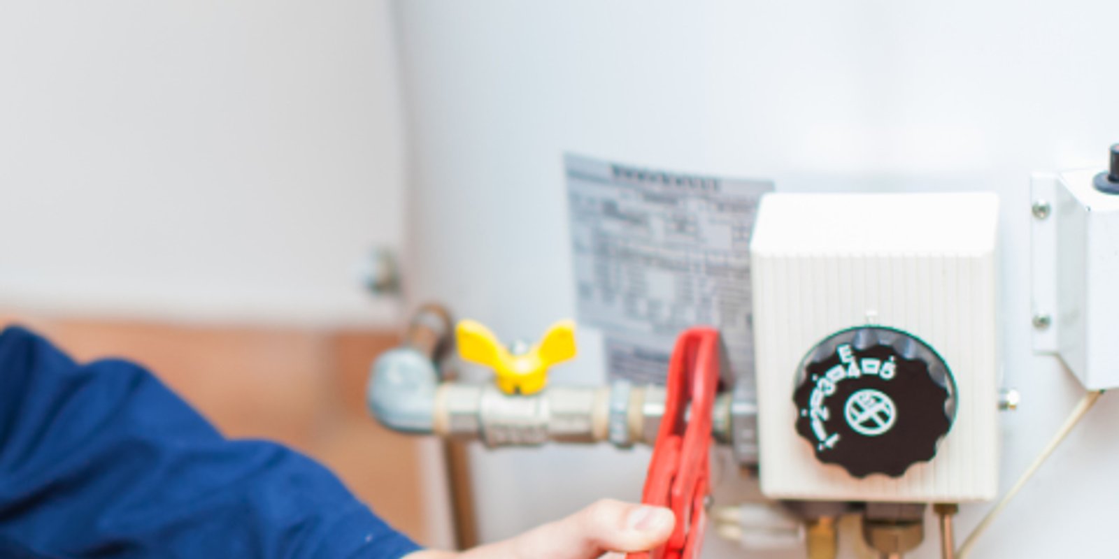 Plumber inspecting the controls and connections on a water heater