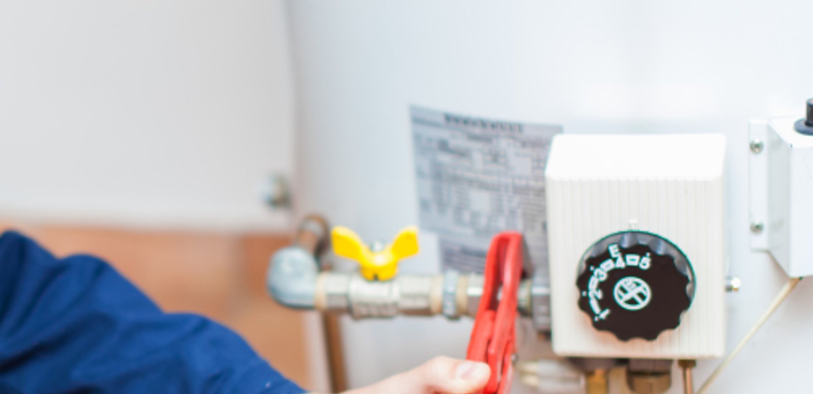 Plumber inspecting the controls and connections on a water heater