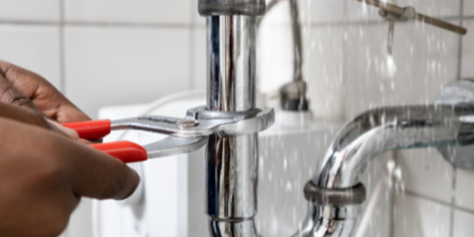 Plumber working on a leaking pipe beneath a sink